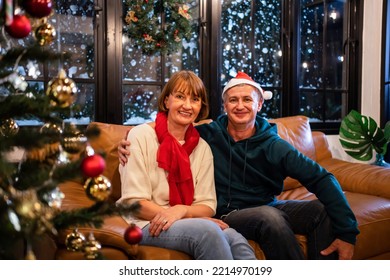 Portrait Of Senior Elderly Couple Celebrate Christmas Party In House. Attractive Mature Older Parents Sitting On Sofa Enjoy Celebrating Holiday Christmas, Thanksgiving At Home And Looking At Camera.