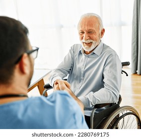 Portrait of senior elderly man with a doctor or male caregiver shaking hands at home or nursing home, people with disability, person with paraplegia and chronic health condition - Powered by Shutterstock