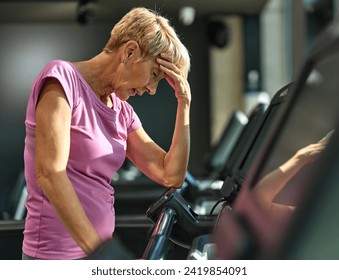 Portrait of a senior elderly woman exercising in a gym, tired mature female running and taking a break using treadmill, healthy lifestyle and cardio exercise at fitness club concepts, vitality  - Powered by Shutterstock