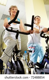 Portrait Of Senior Females Doing Physical Exercise On Special Equipment In Club