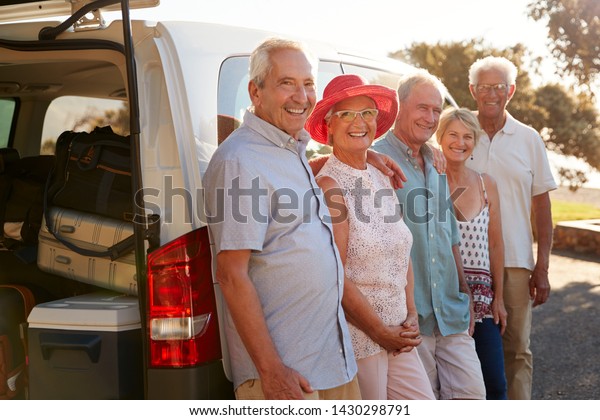 Portrait Of Senior Friends Standing Together\
Beside Van On Vacation