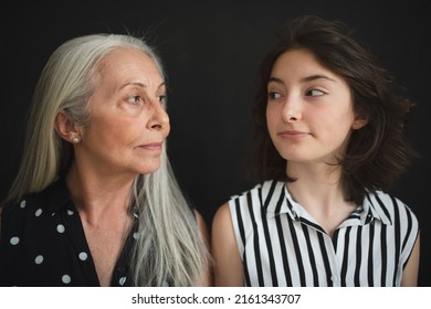 Portrait Of Senior Grandmother With Her Granddaughter Looking At Each Other Over Black Blackground