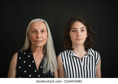 Portrait Of Senior Grandmother With Her Granddaughter Looking At Camera Over Black Blackground