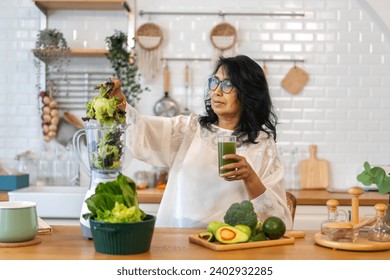 Portrait senior healthy asian woman making green vegetables detox cleanse and green fruit smoothie with blender.elderly woman drinking glass of green fruit smoothie in kitchen.healthcare, insurance - Powered by Shutterstock