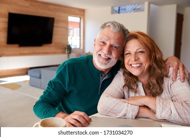 Portrait Of Senior Hispanic Couple At Home Sitting At Table Using Laptop Together