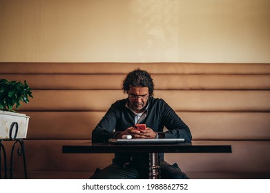 Portrait of a senior hispanic cuban man using smartphone while sitting in a cafe and working