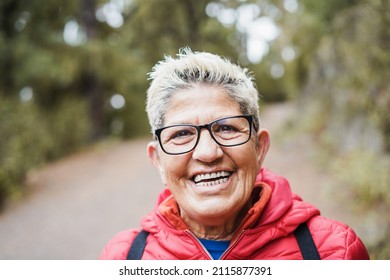 Portrait Of Senior Hispanic Woman Having Fun During Trekking Day In Mountain Forest - Focus On Face