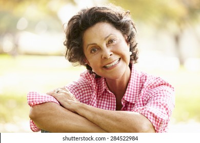 Portrait Of Senior Hispanic Woman Sitting In Park