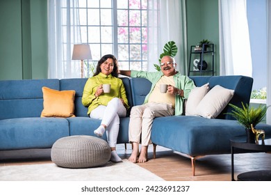 Portrait of senior Indian couple sitting on sofa or stairs and having coffee - Powered by Shutterstock