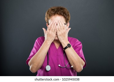 Portrait Of Senior Lady Doctor Covering Eyes Like Blind Concept On Black Background