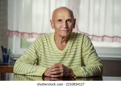 Portrait Of Senior Male Person Seated At Table In Apartment. Candid And Real Human Photography.