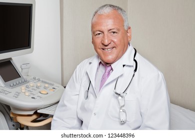 Portrait of senior male radiologist smiling with ultrasonic machine in background