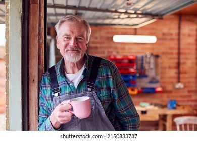 Portrait Of Senior Male Wearing Overalls In Garage Workshop With Hot Drink - Powered by Shutterstock