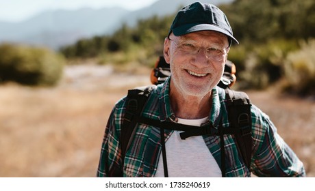 Portrait of a senior man carrying a backpack looking at camera and smiling. Fit old man on a hiking trip. - Shutterstock ID 1735240619