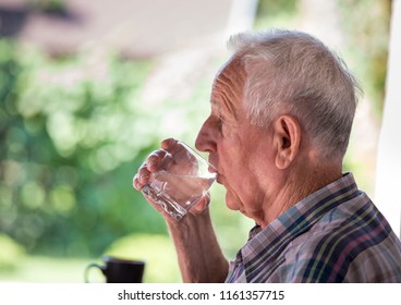 Portrait Of Senior Man Drinking Water From Glass In Garden