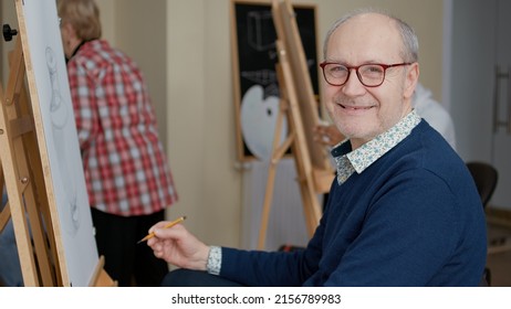 Portrait of senior man enjoying art class to develop drawing skills for personal growth. Elder student attending artistic lesson to learn to draw masterpiece on canvas as new years resolutions. - Powered by Shutterstock