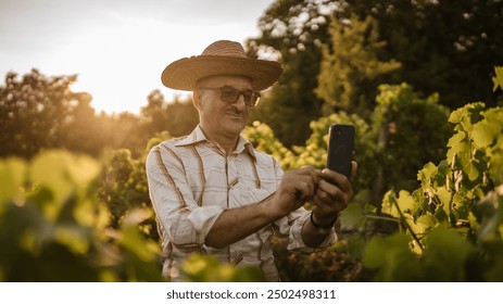 Portrait of senior man farmer stand in the vineyard use mobile phone - Powered by Shutterstock