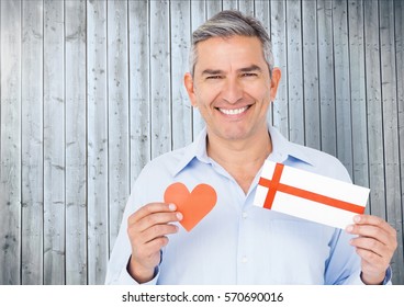 Portrait Of Senior Man Holding Red Heart And Gift Card Against Wooden Background