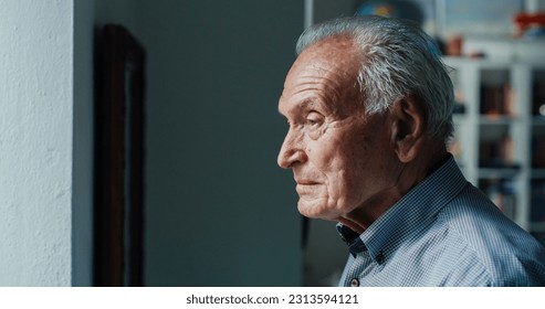 Portrait of a Senior Man at Home Getting Close to a Window and Watching Through it. An Old Man Watching his Family Arrive to Visit him. He is Thoughtful and Feeling Nostalgic - Powered by Shutterstock