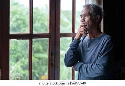 Portrait of a senior man looking through a window A portrait of an old man standing contemplatively near the window. look away and ponder Gray-haired Asian elderly man - Powered by Shutterstock