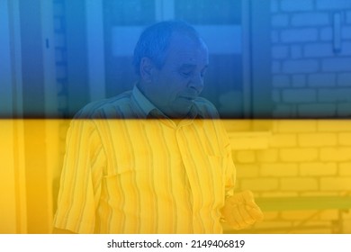 Portrait Of A Senior Man Outdoors. 70s Years Old Latin Or Hispanic Man Standing Outside In Summer Day And Looking Down On His Nails. Casual And Lifestyle Concept. Flag Ukraine.