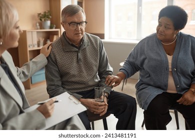 Portrait of senior man sharing mental health struggles in support group session with people comforting him - Powered by Shutterstock