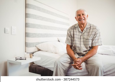 Portrait of senior man sitting on bed and smiling in bedroom - Powered by Shutterstock