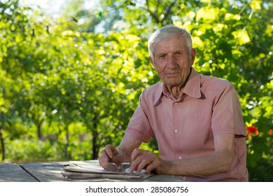 Portrait Of  Senior Man  Sitting At A Table In The Garden
