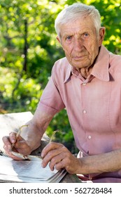 Portrait Of  Senior Man  Sitting At A Table In The Garden
