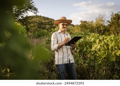 Portrait of senior man stand and hold clipboard in the vineyard - Powered by Shutterstock