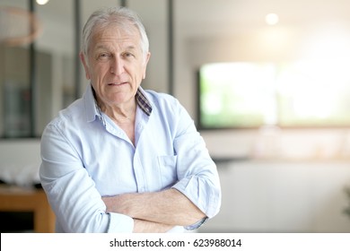 Portrait of senior man standing in living-room