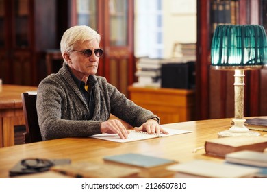 Portrait of senior man with vision impairment reading book in braille at table in classic library - Powered by Shutterstock