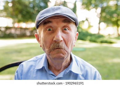 Portrait Of Senior Man With White Mustache Looking At Camera And Making Faces. Man Looking Goofy And Funny With A Silly Cross-eyed Expression, Joking And Fooling Around.