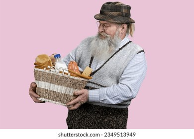 Portrait of senior man with wicher basket with food from grocery shop. Isolated on pink. - Powered by Shutterstock