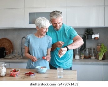 Portrait of a senior mature couple having a healthy breakfast and checking smart watch app cardio performance after fitness exercise training in the morning at home - Powered by Shutterstock