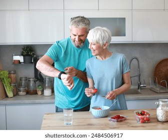 Portrait of a senior mature couple having a healthy breakfast and checking smart watch app cardio performance after fitness exercise training in the morning at home - Powered by Shutterstock