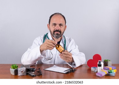 Portrait Of Senior Mature Doctor Holding Medicine Bottle And Looking At Camera