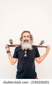 Portrait Senior Or Mature Latino Man With Gray Beard Holding A Skateboard