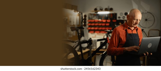 Portrait of senior mechanic worker in his workshop using laptop computer repairing bike. Small business concept - Powered by Shutterstock