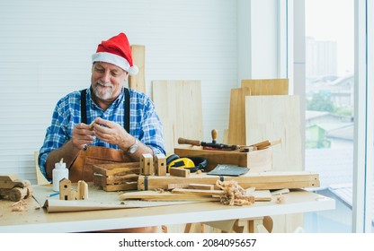 Portrait senior old aging kind Caucasian man or carpenter wearing santa hat, making DIY wooden furniture, smiling with happiness, sitting alone at home. Retirement, Hobby Concept - Powered by Shutterstock