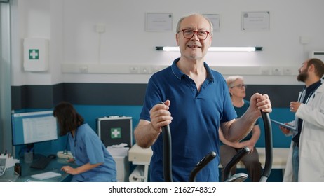 Portrait of senior patient using stationary bicycle for recovery program and rehabilitation. Old man doing physiotherapy and trying alternative medicine to cure mechanical disorders. - Powered by Shutterstock