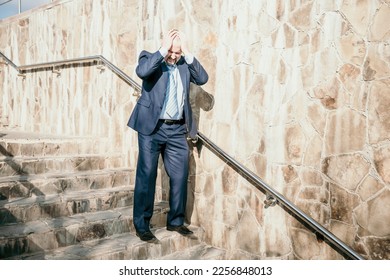Portrait of a senior professional man in a suit with various problems. A middle-aged businessman with descends the stairs. - Shutterstock ID 2256848013