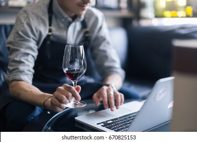 Portrait of senior sommelier sitting in front of laptop at wine cellar and tasting red wine while working together. Small business. - Powered by Shutterstock