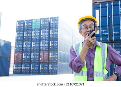 Portrait Senior Warehouse Staff With Yellow Hard Hat, Construction Vest And Walky Talky Working And Checking Container Number For Freight And Sea Cargo. Elder Worker Healthy And Happiness.