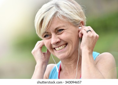 Portrait of senior woman adjusting earphones before exercising - Powered by Shutterstock