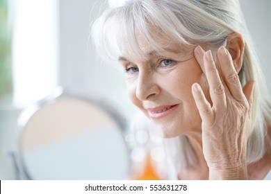 Portrait of senior woman applying anti-aging cream