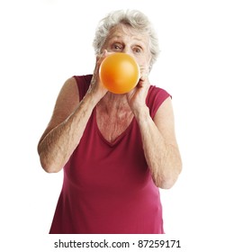 Portrait Of Senior Woman Blowing A Balloon