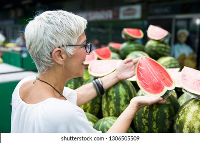 Portrait Of Senior Woman Buying Watermelon On Market