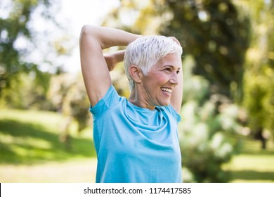Portrait of senior woman doing exercise for stretching arms in the park