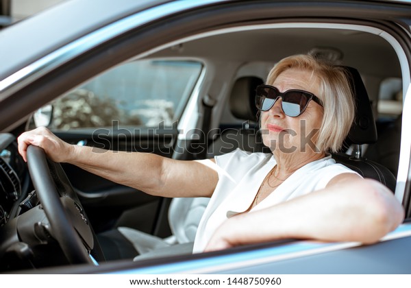 Portrait of a senior woman driver sitting in the\
modern car